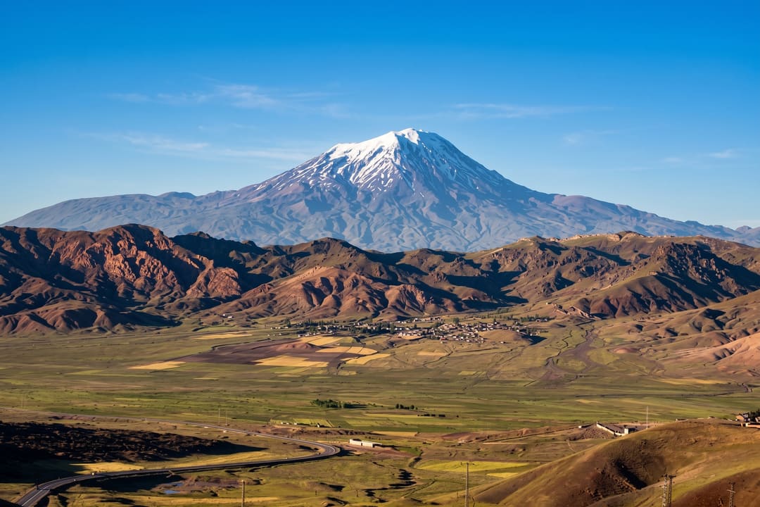 O Monte Ararate, com o cume coberto de neve, visto de longe sobre os vales cultivados da região